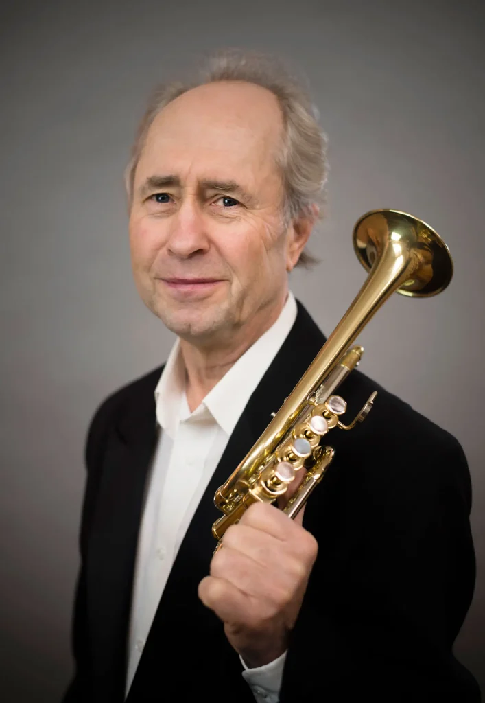 Musician in a dark jacket holding a trumpet