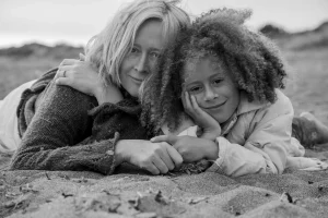 Mother and child lying on a sandy beach, black and white