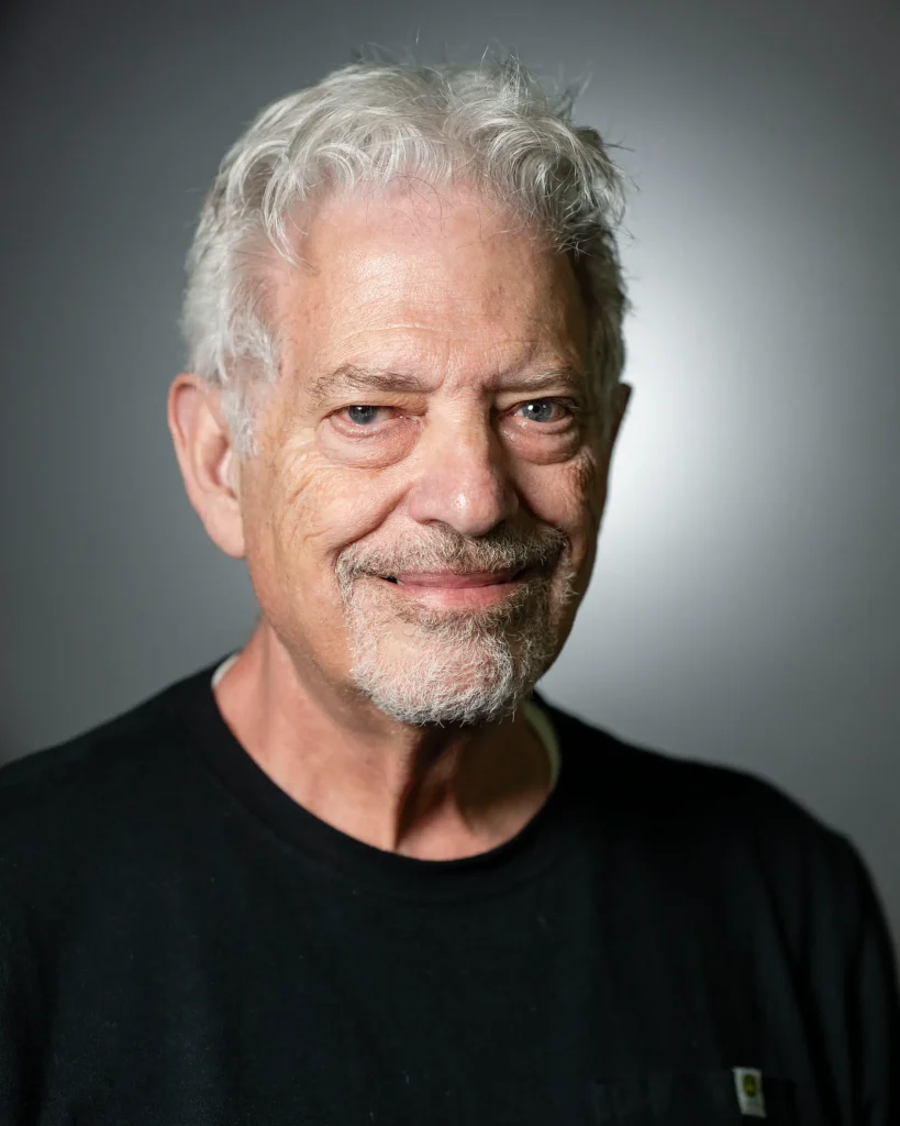 Older man with white hair, grey studio backdrop