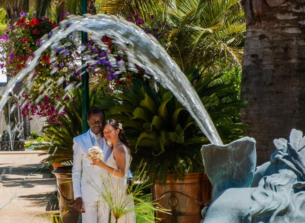 Bride and groom framed by the arc of a garden fountain