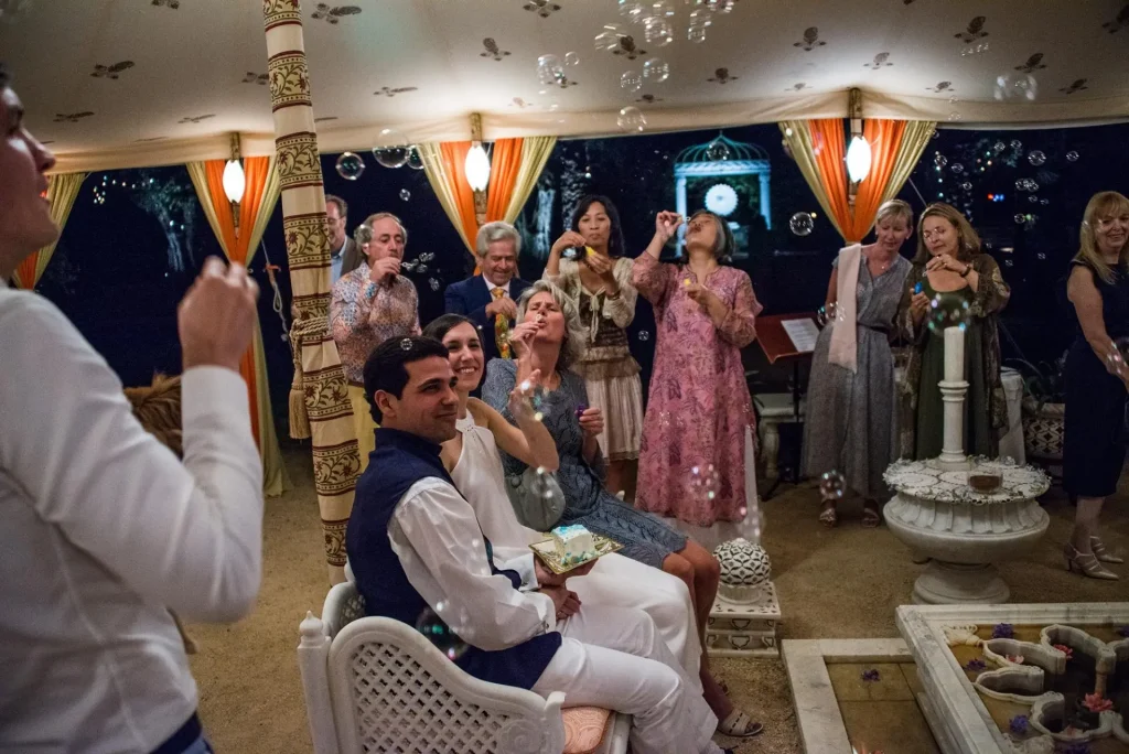 Couple seated in a lantern-lit tent while guests blow soap bubbles