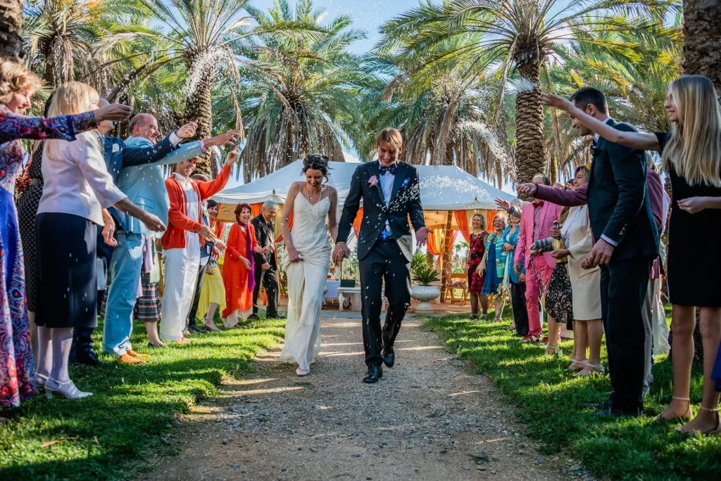 Newlyweds walking down a grassy aisle as guests shower them with petals