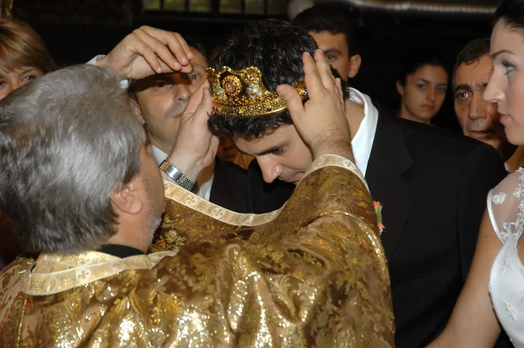 Priest placing a golden crown on the groom during an Orthodox wedding