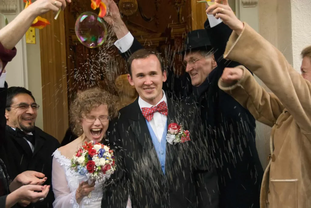 Laughing newlyweds showered with rice outside the church